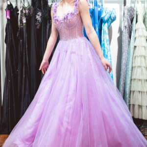 Step into a fairytale in this enchanting lilac ballgown, featuring delicate 3D floral appliqués and a graceful scoop neckline. Lilac ballgown with 3D floral appliqués and scoop neckline for a romantic and whimsical prom look.